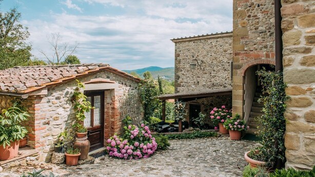 A stone building with a tiled roof, a small entrance, and potted plants. - Villa Il Gufo - Seven Bedroom Villa, Sleeps 20 (Anghiari)