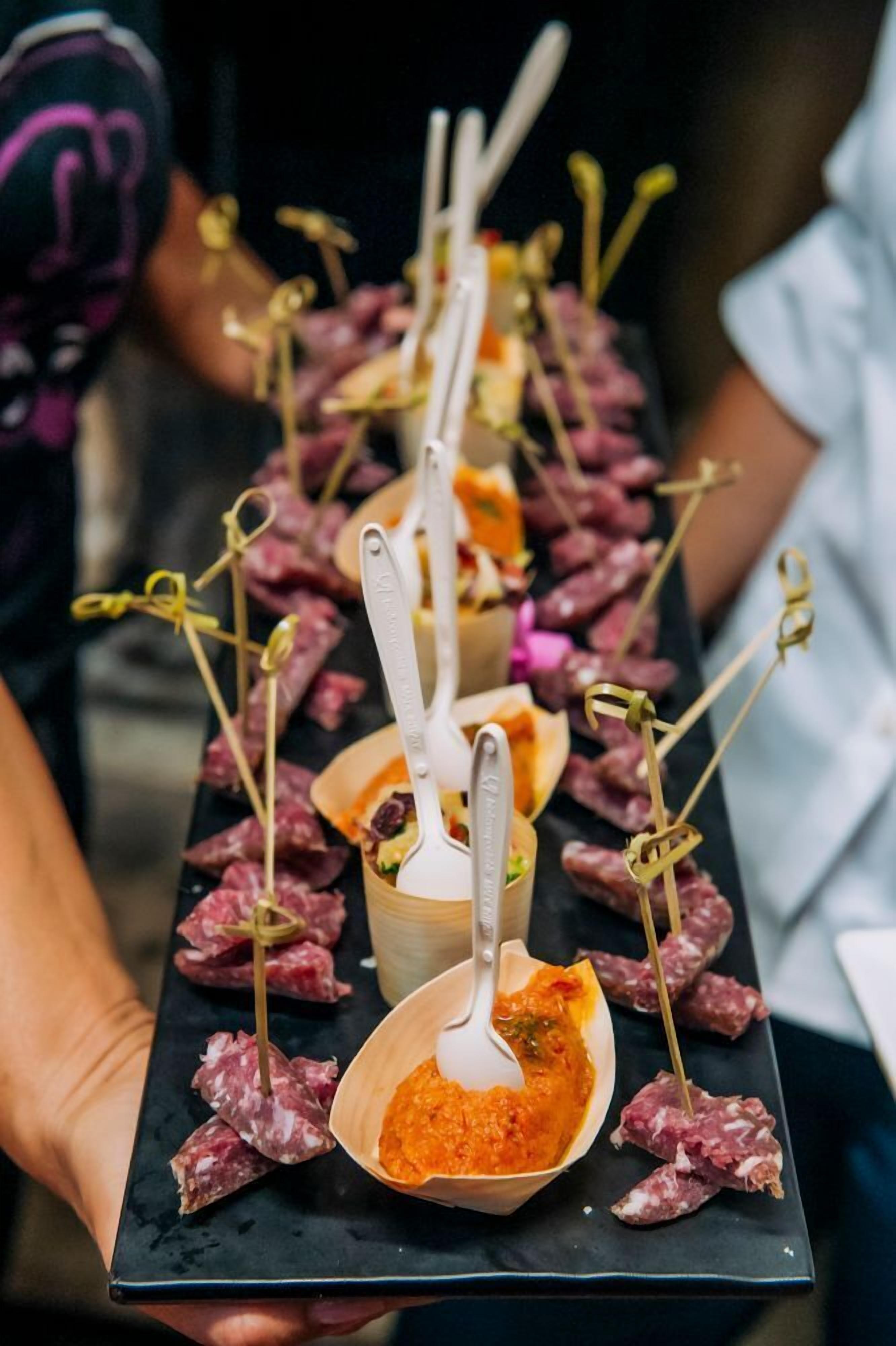 Un plateau contenant divers aliments, notamment de la viande et un bol de sauce, est tenu par une personne.