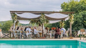 An outdoor wedding reception with a pool, covered seating area, and lush greenery in the background. - Villa Il Gufo - Seven Bedroom Villa, Sleeps 20 (Anghiari)