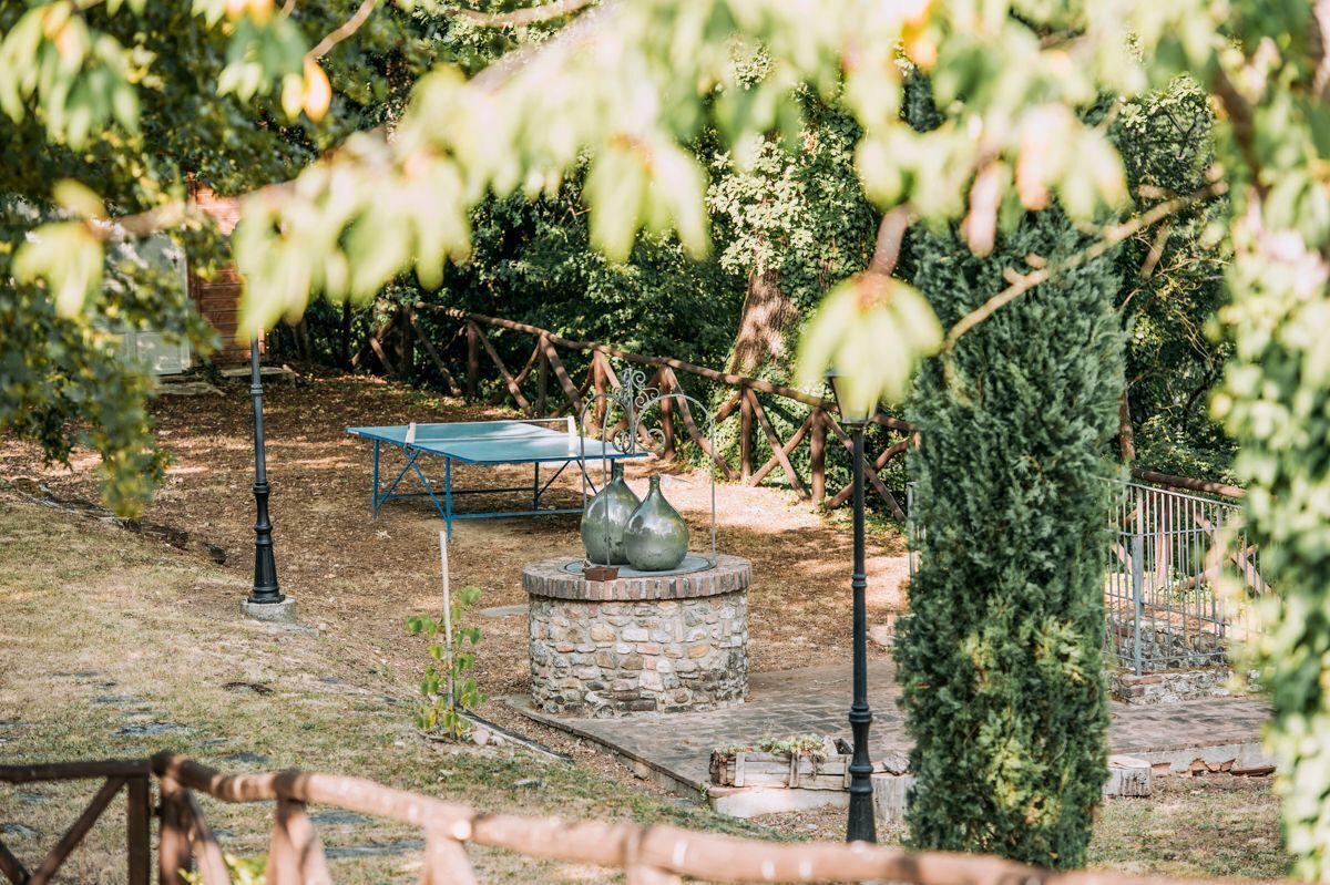 Un jardin agrémenté d’une fontaine en pierre, d’un banc en métal et d’une clôture en métal.