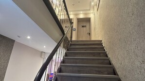A staircase with a handrail, a door at the top, and a wall with a textured surface. - Suite-Pauli (Hamburg)