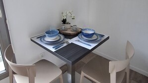 A dining area with a table set for four, two chairs, a vase with flowers, and two framed pictures on the wall. - Cosy studio • 5 min from station and center - Very bright and quiet (Amiens)