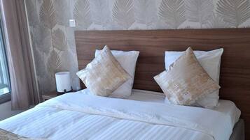 A hotel room with a large bed, a wooden headboard, and a patterned wallpaper.