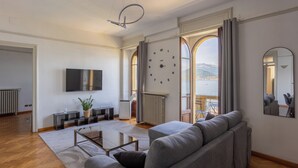 Ett modernt vardagsrum med en soffa, en tv och utsikt över havet genom stora fönster.