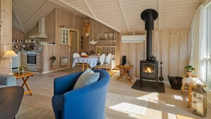 Een gezellig interieur van een chalet met een eethoek, keuken en een houtkachel.