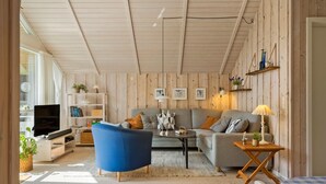 Een gezellige woonkamer met een blauwe fauteuil, een grijze bank en een televisie.