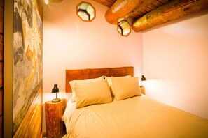 Un dormitorio con cabecera de madera, dos lámparas de noche y un cuadro en la pared.