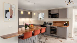 Eine moderne Küche mit einer Holztheke, Barhocker, einem eingebauten Ofen und einer Mikrowelle.