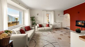 Ein modernes Wohnzimmer mit zwei Sofas, einem Kamin, einem großen Fenster mit Aussicht und einer roten Akzentwand.