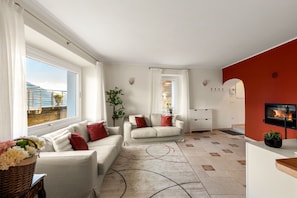 A modern living room with two sofas, a fireplace, a large window with a view, and a red accent wall. - Dolce Riva - Three Bedroom Villa, Sleeps 8 (Acquaseria)