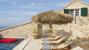 A pool area with lounge chairs and a thatched umbrella, overlooking a beach and the sea. - Villa Amarant - Five Bedroom Villa, Sleeps 10 (Zavala)