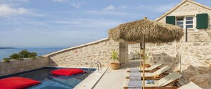 A pool area with lounge chairs and a thatched umbrella, overlooking a beach and the sea. - Villa Amarant - Five Bedroom Villa, Sleeps 10 (Zavala)