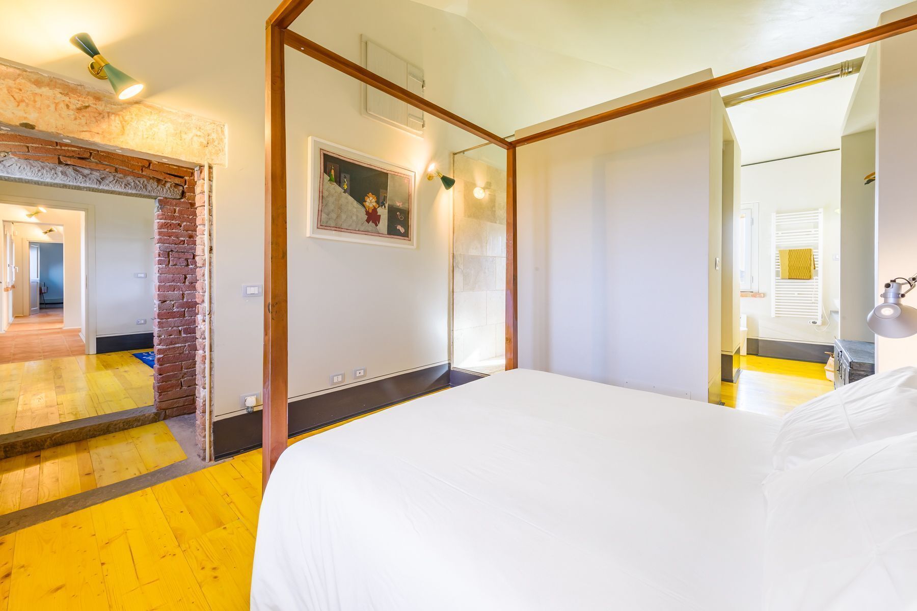 Une chambre d’hôtel avec un lit, un miroir, un tableau au mur et un plancher en bois.