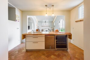 Una cocina moderna con lavavajillas, un lavabo y horno empotrado. Hay una ventana que proporciona luz natural y vistas al exterior.
