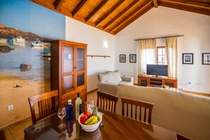 A room with a wooden ceiling, a bed, a TV, and a dining area with a table and chairs. - Villa Lajares Dos - Two Bedroom Villa, Sleeps 4 (Lajares)