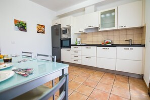 Eine moderne Küche mit weißen Schränken, einem Edelstahlkühlschrank und einer gefliesten Spritzschutzwand.