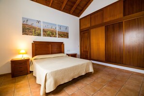 Ein Schlafzimmer mit einem hölzernen Bett, einem Nachttisch, einer Lampe, einem Kleiderschrank und drei Wandbildern.