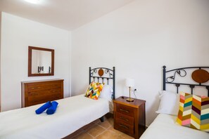 Ein Hotelzimmer mit zwei Einzelbetten, einem Holzschrank, einem Nachttisch mit Lampe und einem Spiegel an der Wand.