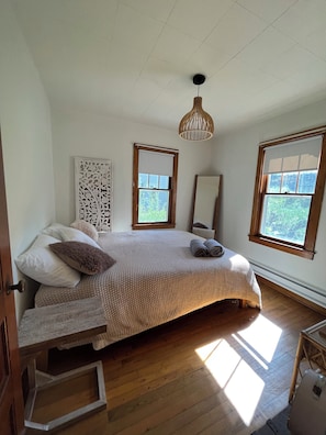 A bedroom with a bed, a window, a ceiling light, and a door.