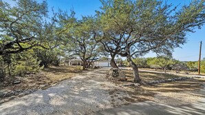 Un quartiere residenziale con vialetto sterrato, alberi e una casa con garage.