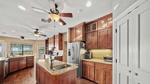 Un'ampia cucina con mobili in legno, un'isola centrale con lavello e una ventola a soffitto.
