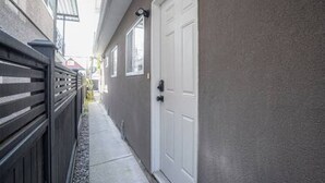 A narrow alleyway with a white door, a dark fence, and a building with a window. - Chic 2BR Mount Pleasant Suite Near Downtown (Vancouver)