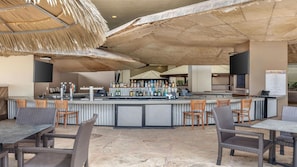 Ein Außenbereich mit Bar, einer Theke, Barhocker und einer Speisekarte mit der Aufschrift 'Makai Bar'.