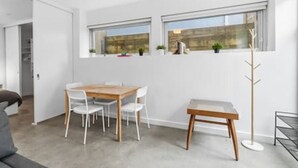 A modern room with a dining table, chairs, a coat rack, and a window with a view. - Bright Private-Entrance Suite, Quiet East Van (Vancouver)