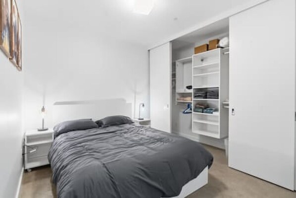 Un dormitorio con cama, mesitas de noche, armario y ropero.