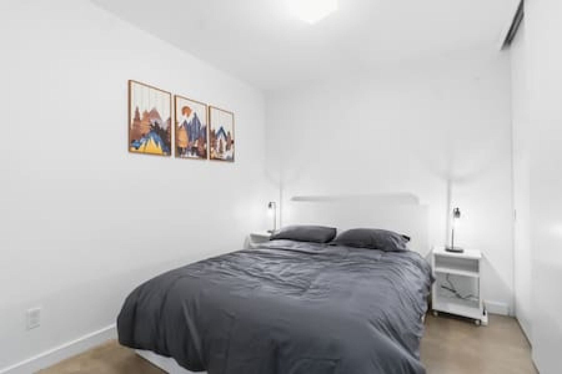 A bedroom with a bed, two bedside tables, and wall-mounted lamps.
