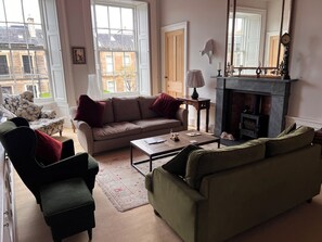 A living room with a sofa, armchair, coffee table, fireplace, and large windows. - Luxurious apartment in the New Town. Walking distance from central Edinburgh (Edinburgh)