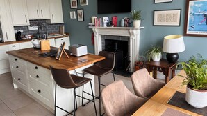 A modern kitchen with white cabinets, a wooden island, bar stools, a fireplace, and a flat-screen TV. - Luxurious apartment in the New Town. Walking distance from central Edinburgh (Edinburgh)