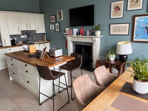 A modern kitchen with white cabinets, a wooden island, bar stools, a fireplace, and a flat-screen TV. - Luxurious apartment in the New Town. Walking distance from central Edinburgh (Edinburgh)