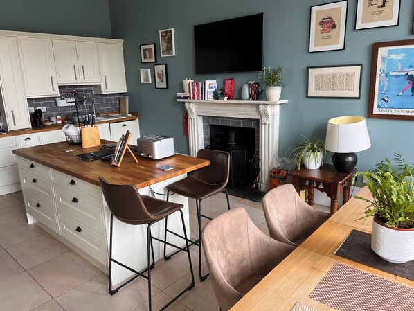 A modern kitchen with white cabinets, a wooden island, bar stools, a fireplace, and a flat-screen TV. - Luxurious apartment in the New Town. Walking distance from central Edinburgh (Edinburgh)