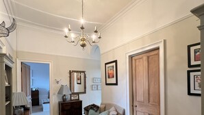 A spacious hallway with a chandelier, a sofa, a wooden door, and a patterned rug. - Luxurious apartment in the New Town. Walking distance from central Edinburgh (Edinburgh)