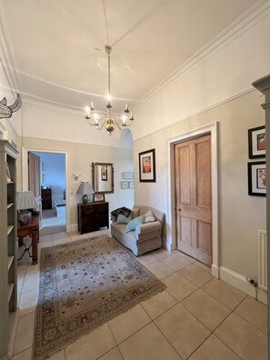 A spacious hallway with a chandelier, a sofa, a wooden door, and a patterned rug. - Luxurious apartment in the New Town. Walking distance from central Edinburgh (Edinburgh)