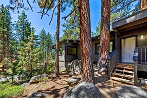Eine Holzhütte mit einer Holzdiele, umgeben von Bäumen und Felsen.