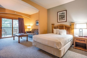 A hotel room with a bed, a desk, a chair, a pool table, and a balcony with a view.
