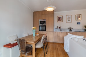 Eine moderne Küche mit Holzschränken, einem Esstisch mit Stühlen und einem weißen Sofa.