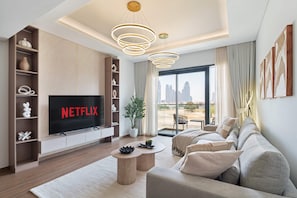 Ein modernes Wohnzimmer mit Flachbildfernseher, einer Couch, einem Couchtisch und einem großen Fenster mit Blick auf die Stadt.
