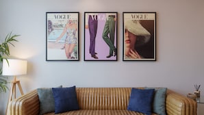 A room with a brown leather sofa, three framed magazine covers on the wall, and a lamp on a side table. - Chic 2BR in Paramount Midtown Infinity Pool Access (Dubai)