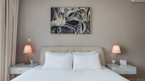A hotel room with a bed, two bedside tables, lamps, a water bottle, and a framed artwork on the wall. - Chic 2BR in Paramount Midtown Infinity Pool Access (Dubai)
