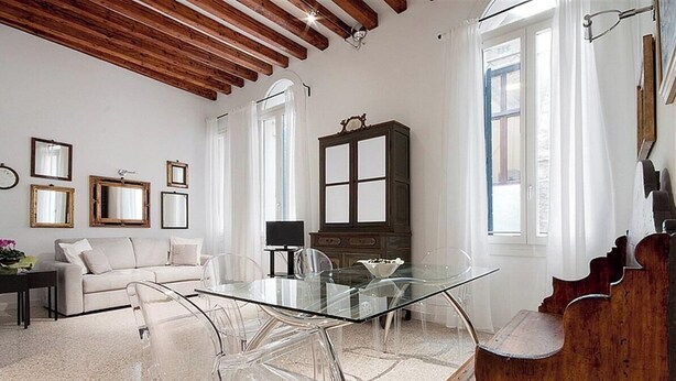 A room with a glass dining table, a sofa, a wooden cabinet, and a piano. - Stradivari apartment in Venice historic center (Venezia)