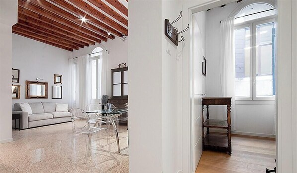 Un soggiorno moderno con soffitto in legno, un divano, un tavolino in vetro e sedie.