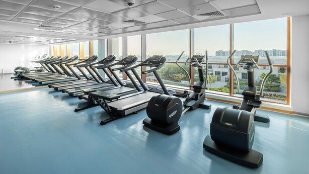 A gym with treadmills, ellipticals, and weight machines arranged in rows. - Free Housekeeping Visits During Your Stay - Stayshort - Cozy Townsquare 1 Bed Apartment With Balcony That Sleeps 4 (Dubai)