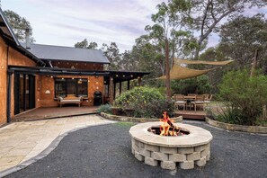 Ein Gebäude mit einer überdachten Terrasse, Sitzgelegenheiten im Freien und einer Feuerstelle.