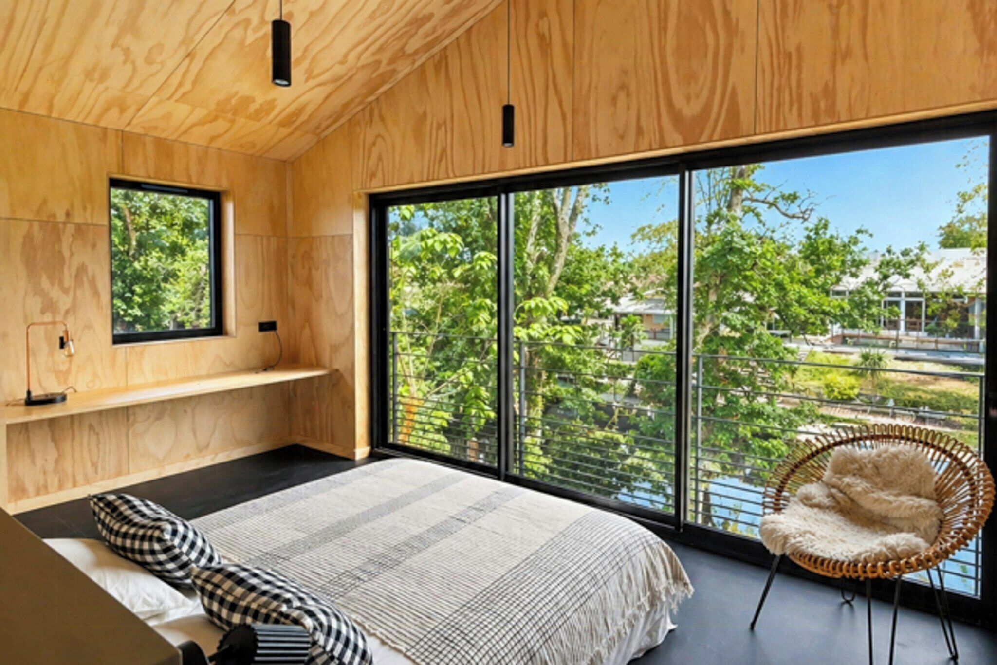 A bedroom with a large window, a bed, a chair, and a shelf.