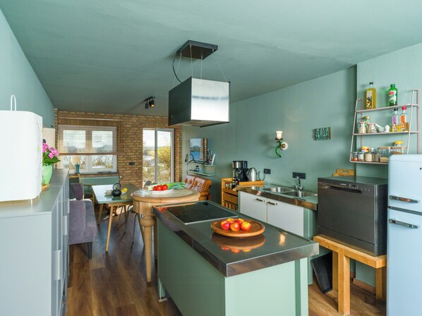 Cocina compacta con una isla central, horno empotrado y refrigerador.