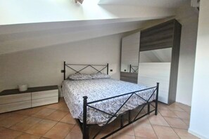 Una camera da letto con un letto, una cassettiera, uno specchio e un armadio.