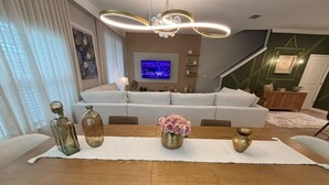 Una sala de estar moderna con una mesa de comedor, sofás y una televisión.